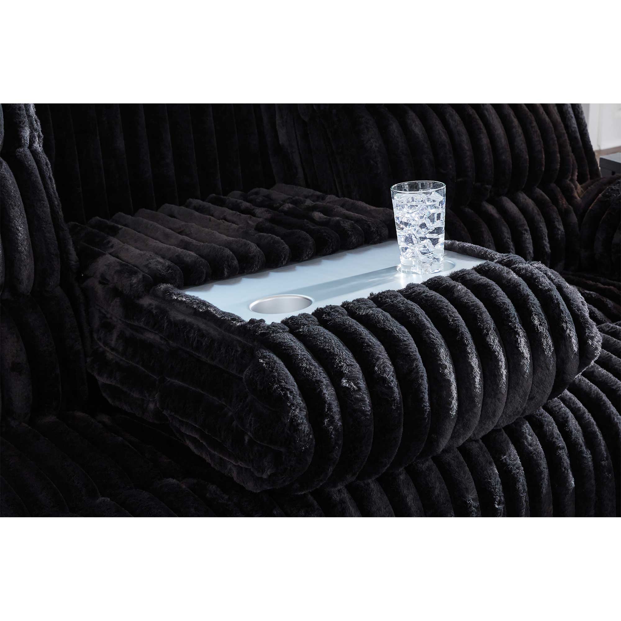 Black textured armchair with a small table and glass of water on a white background